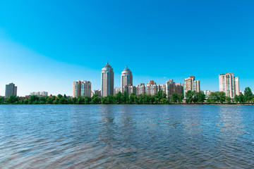 Fototapeta premium City on the coast of the lake. Tall residential buildings on the shore of a wide lake