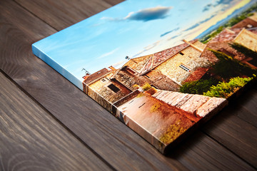 Canvas photo print on brown wooden background. Side view of colorful photography with gallery wrap....