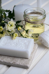 Obraz na płótnie Canvas Handmade soap with a pattern lies on the table. On a white table is handmade soap, flowers and olive oil. Collection of items for the bathroom
