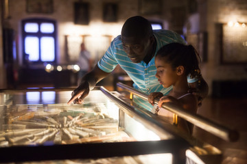 Man and his daughter looking at showcase with exhibits
