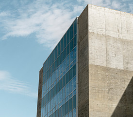 Corner of a modern concrete building and large glazed windows with turquoise tones