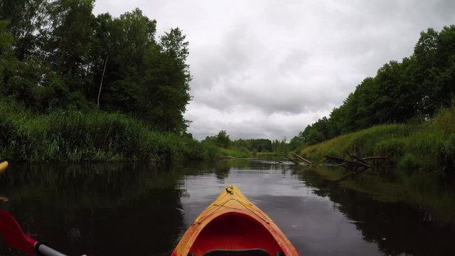 Point of view ,POV Perspective View of canoe, footage from inside of kayak.  Man paddling on a river, people are jumping from cliffs. Summer or spring, sunny weather. Concept: summer activities.