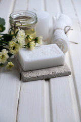 Obraz na płótnie Canvas Handmade soap with a pattern lies on the table. On a white table is handmade soap, flowers and olive oil. Collection of items for the bathroom