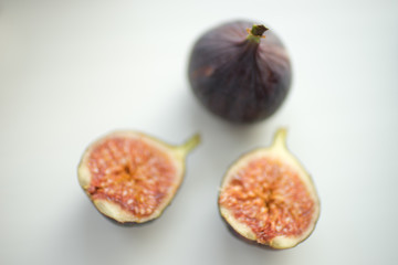 One whole fig and the second cut in half lie on a white table.
