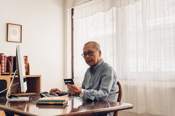 Senior man shopping online using computer and credit card.