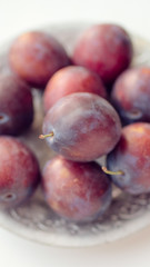 Ripe purple plums in a silver plate closeup.