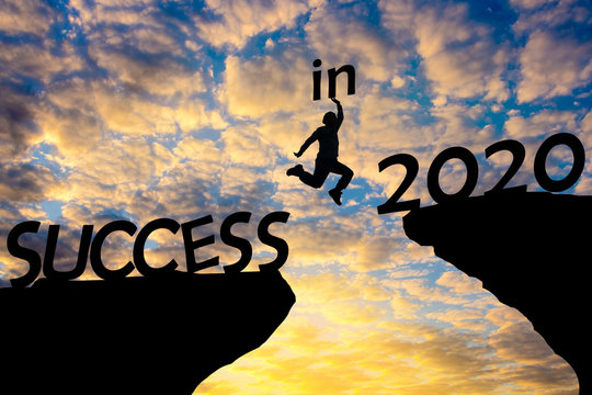 Silhouette sunset background.man is jumping over to cliff and jump  across between success and 2020 word.This photo shows about freedom,Active and successful,Photo concept  silhouette and new year.