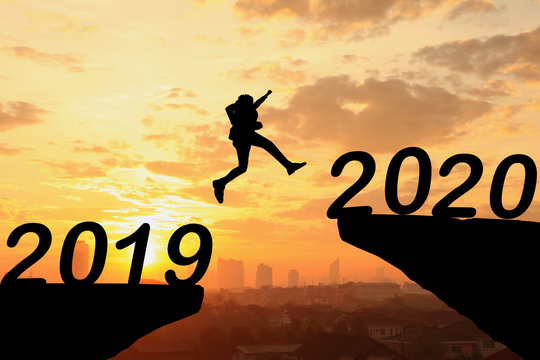 Happy new year Silhouette sunset background. A man jumping over cliff and jump between 2019 and 2020 years. Photo Silhouette and new year  concept idea.