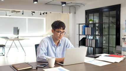 Naklejka premium Young asian businessman concentrate on working with laptop computer at office, Asian office man comtemplate on working with laptop computer business people and office lifestyle concept