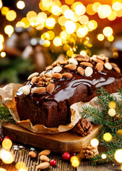 Christmas gingerbread cake covered with chocolate and decorated with nuts and almonds on the holiday table. Christmas dessert
