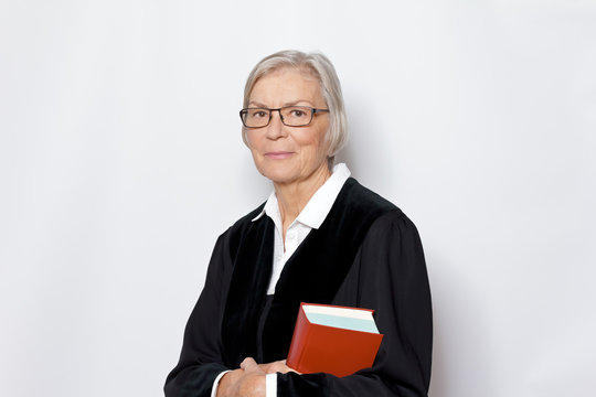 Female jurisdiction concept: mature german woman in a black judge's gown holding a legislative text book.