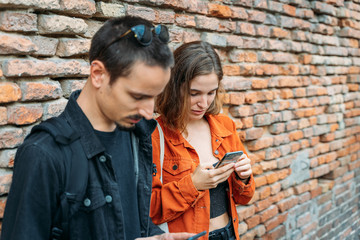 Couple in front of a brick wall looking at the mobile