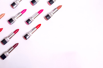 lots of colorful lipsticks lined up in army shape on white background