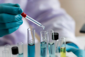 Fototapeta premium Laboratory concept; Scientist use dropper to transfer chemical reagent to test tube. He observe the chemical reaction in laboratory.