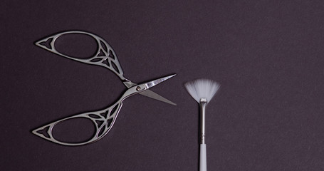 white brush and beautiful openwork scissors for nail design on black background