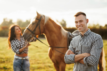 Obraz premium Portrait of happy loving couple spending time with horses on ranch