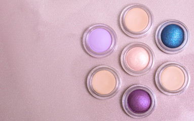 round multicolored eye shadows are arranged in the shape of a flower on a gold background with copy...