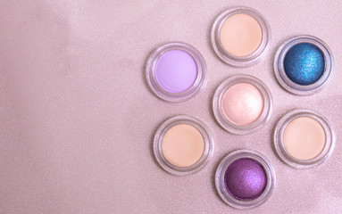 round multicolored eye shadows are arranged in the shape of a flower on a gold background with copy space