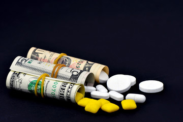Dollar rolled up with pills flowing out isolated on black background, high costs of expensive medication concept. Copy space - image