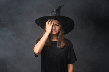 Girl with witch costume for halloween parties over isolated dark background having doubts with confuse face expression