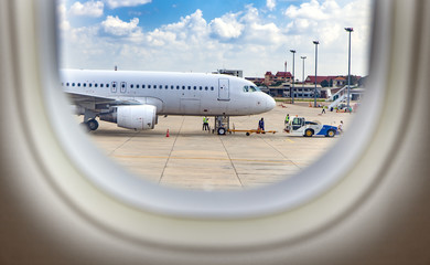 Fototapeta na wymiar View trough window of aircraft at Airplane standing on International Airport.