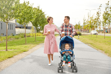 family, leisure and people concept - happy mother and father with little son in stroller and takeaway coffee walking along city street