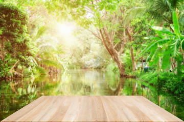 Empty wooden desk of free space and spring time with Morning sun light with wind blowing leaves in the lake park,Template mock up for display montages of product.