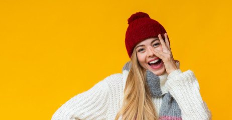 Joyful blonde girl posing over yellow studio background