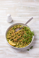 Stewed chickpeas in green sauce with parsley and lemon on a white wooden background, rustic style, top view. delicious healthy homemade food 