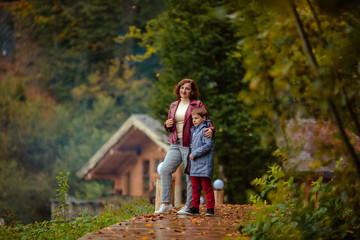 Travelers mother and son on a walk in the autumn mountains against the background of a wooden house from a log house