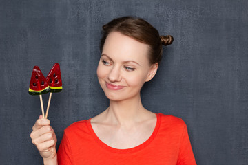 Portrait of cheerful woman holding two lollipops in hand