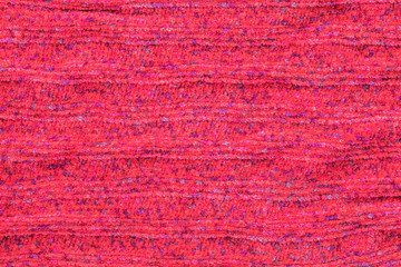 Background in the form of knitted material from red wool with horizontal stripes and blue spots