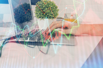 Multi exposure of graph with man typing on computer in office on background. Concept of hard work. Closeup.