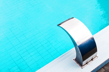 Blue swimming pool with a modern stainless steel water flowon massage tap on a beautiful summer afternoon for background, high resolution