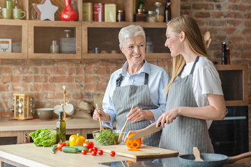 Friendly mother and daughter making healthy dinner together