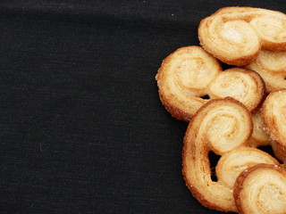 Heart-shaped puff pastry (palmeritas) with a black background. (negative space).
