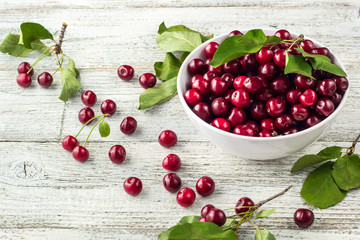 Fresh sweet cherries white bowl with leaves in water drops on wooden background