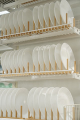 a lot of Rack with clean dishes. white dishes hanging on the racks on the shelf 