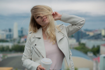 blonde in a white leather jacket tilted her head and the wind ruffled her hair.