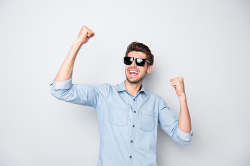 Portrait of delighted guy in black spectacles feel euphoria just won contest raise fists scream...
