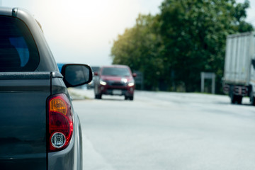 Pick up black color car stop on the asphalt junction by traffic light control in across. Traveling in the provinces during the bright period. with tree beside road.