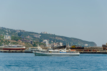 A white passenger ship enters the port in the summer.