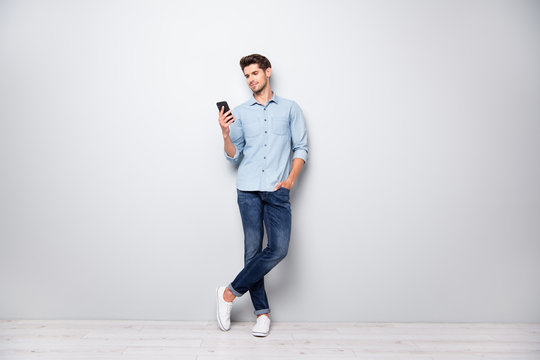 Full size photo of concentrated smm worker man use cellphone answer sms messages have online conversation with friends type comments posts wear stylish outfit sneakers isolated grey color background