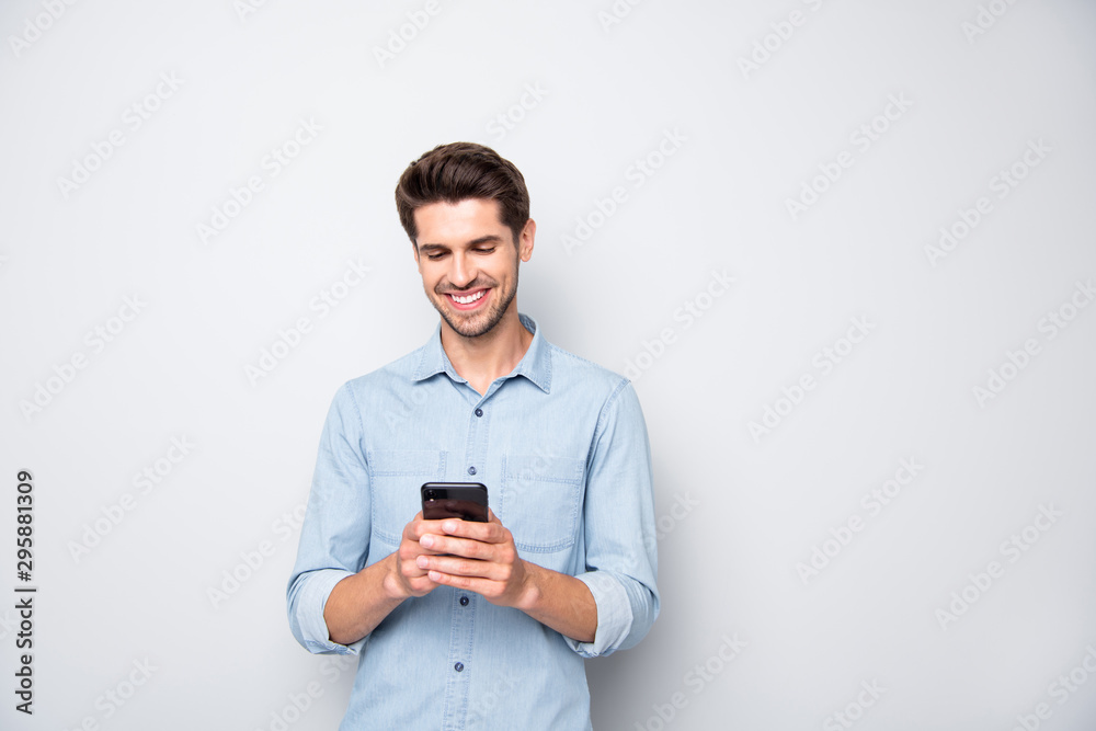 Sticker Portrait of positive cheerful man stand copyspace have fun use his smartphone type new post in blog enjoy feel content wear style clothes isolated over grey color background