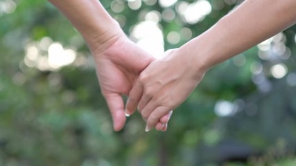 Close-up of hands joining together on bokeh background. Beautiful romantic moment between two lovers