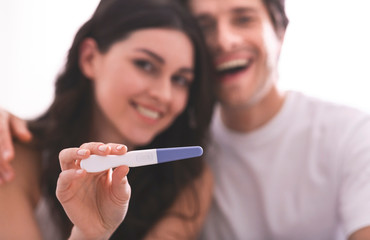 Happy couple showing pregnancy test on camera