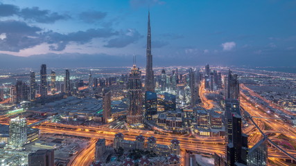 Dubai Downtown skyline futuristic cityscape with many skyscrapers and Burj Khalifa aerial night to day timelapse.