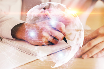 Double exposure of Man writing in notepad with business icons on background.