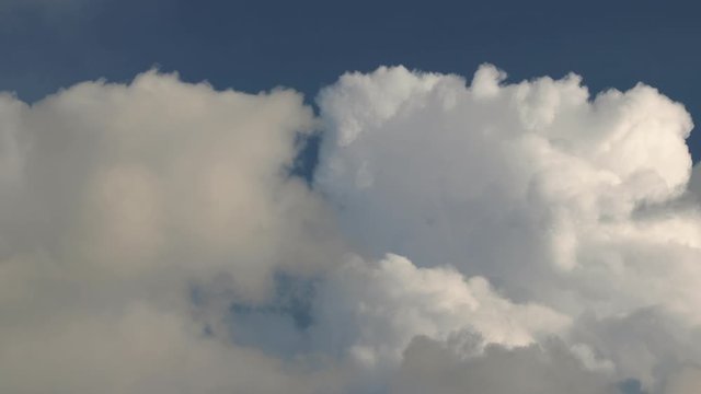 Clouds moving in the blue sky in opposite direction, realtime footage, closing in