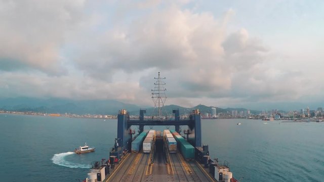 Cargo transportation by ferry across the sea. The ship is leaving the port. Time lapse shooting. A huge ship smuggles large truck wagons with goods on board. Import and export to other countries.